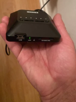 Svart digital mediaspelare LogiLink - Digital mediaspelare från LogiLink i svart plast med USB-port, SD/MMC/MS-kortläsare, HDMI-utgång och IR-sensor. Kompakt och smidig design, perfekt för att spela upp mediafiler från olika källor direkt till TV eller skärm.