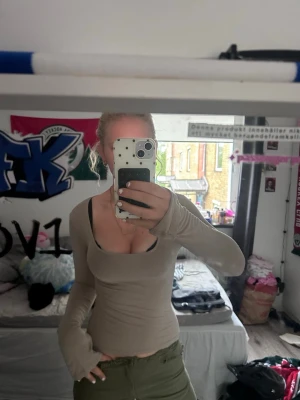 Beige långärmad topp med fyrkantig ringning - Snygg beige långärmad topp med fyrkantig ringning och tight passform. Perfekt att styla med jeans eller kjol för en trendig look. Mjuk och stretchig i materialet för extra komfort.
