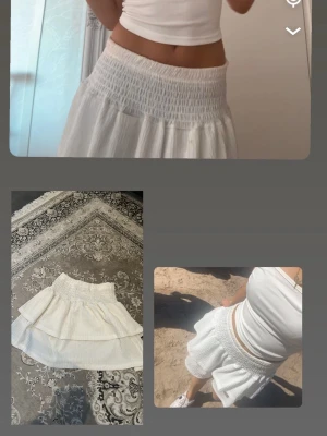 Vit volangkjol med smock i midjan - Söt vit kortkjol med bred smock i midjan och volangdetaljer. Kjolen har en luftig och flowy känsla, perfekt för varma dagar. Passar till både enkla toppar och sneakers för en avslappnad look.