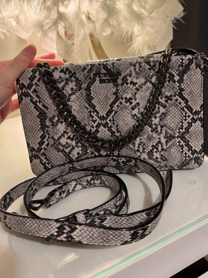Grå ormmönstrad handväska Victoria secret - Väldigt bra skick, avtagbar bälte. Rymlig plats. Finns i Jönköping men kan skickas.