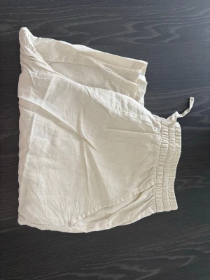 100% linneshorts - Säljer ett par ljusbeiga linnebyxor med avslappnad passform och bred resår i midjan. Byxorna har dragsko och sidofickor, perfekta för en chill och luftig stil. Materialet är 100% linne vilket gör dem svala och sköna.