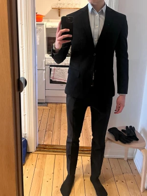 Mörkblå kostym från Filippa K - En skitsnygg kostym från Filippa K, köpte den inför studenten men har nu växt ur den (tyvärr på bredden). Kostymen är använd 8 gånger sen köp och har inga defekter.   Kostymen kemtvättas innan köp                          Kan provas på plats  Jag är 194cm lång och väger ca 78kg  Kostymens mått:    Kavaj:         Bröstvidd: 48cm          Axelbredd: 45cm         Rygglängd 70cm        Byxa:         Midjebredd: 43cm         Innerbenslängd: 89cm         Ytterbenslängd: 107cm         Fotvidd: 17cm  