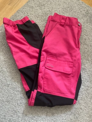 Rosa och svarta byxor från CRW - Snygga byxor i stark rosa färg med svarta detaljer från CRW. Knappt använda säljer då de inte längre passar mig