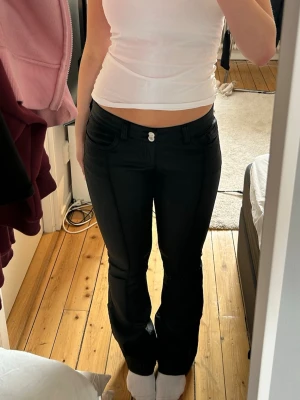 Svarta bootcut jeans - Snygga svarta bootcut jeans med dubbla silverknappar i midjan och klassiska fickor fram och bak. Använda en gång så nästan nyskick! Säljer på grund av att de ej används. Nypris 699kr.