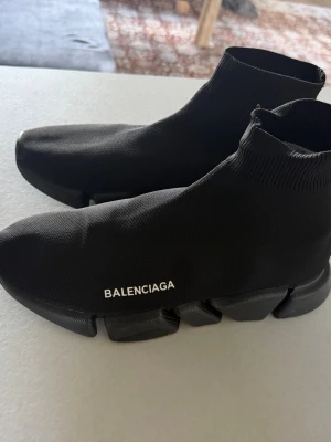 Balenciaga svarta sock sneakers - Svarta sneakers från Balenciaga med stickad ovandel i strumpliknande modell och chunky, futuristisk sula. Diskret Balenciaga-logga på sidan. Skorna har en tight passform och är tillverkade i textilmaterial med elastisk ribbad kant.