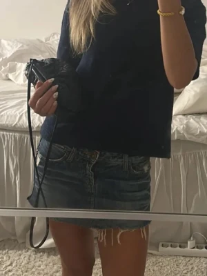Blå jeanskjol med rå kant - Snygg kort jeanskjol i blå denim med rå, fransad nederkant och klassiska fickor fram och bak. Perfekt för dig som gillar en avslappnad och trendig stil. Kjolen har normal passform och stängs med dragkedja och knapp.