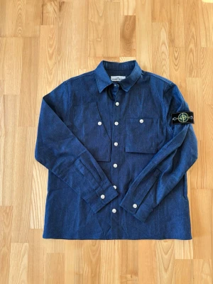 Blå overshirt från Stone Island - Snygg blå overshirt från Stone Island i denimliknande material. Är som en tjockare skjorta eller tunn overshirt. Helt ny och oandvänd. Skickas snabbt 📦.