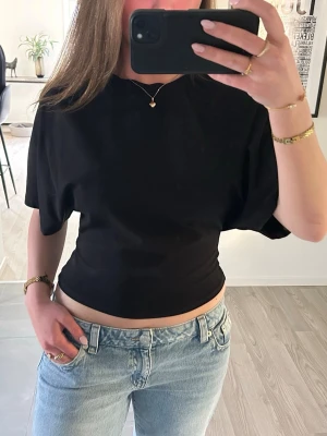 Svart t-shirt - Svart croppad t-shirt med korta, vida ärmar och åtsittande midja från Nelly❣️Storlek M, töjbart material