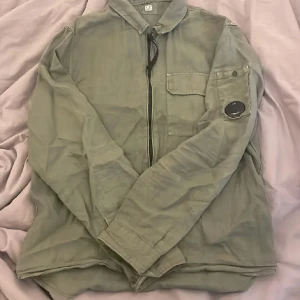 Grön overshirt från C.P. Company - Säljer min mörk gröna Overshirt/ skjorta i linne, den är i bra skick inte använt den många gånger då den inte riktigt passade mig i stilen så bra, hör av er vid frågor! Priset är inte hugget i sten🙌