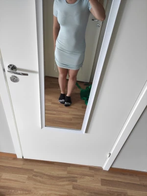 Ljusblå tight kortklänning - Snygg ljusblå kortklänning med tight passform och korta ärmar. Klänningen har snörning i sidorna som ger en cool detalj och gör att du kan justera längden. Perfekt för dig som gillar en enkel men trendig stil.