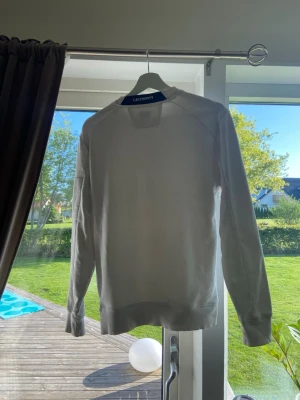 Vit sweatshirt från Geographical Norway - Säljer en stilren vit cp company tröja. Tröjan har rund hals, långa ärmar och en cool detalj med ficka och svart dragsko på ena ärmen. Perfekt för en clean och avslappnad look. Nedsatt pris pågrund av att jag ej har möjlighet att skicka med plastmärket!!