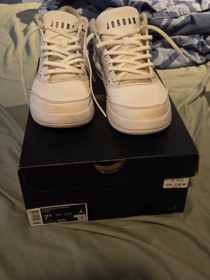 Vita Air Jordan sneakers i läder - Säljer ett par vita Air Jordan sneakers i läder med perforerade sidopaneler och klassisk snörning. Skorna har en låg silhuett och diskret svart detalj vid snörningen. Snygg och stilren modell som passar till det mesta.