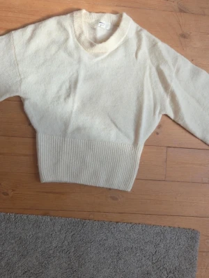 Stickad tröja med ribbad kant - Mysig krämvit stickad tröja med ribbade muddar som sitter åt mot kroppen. Tröjan är från Gina Tricot och är i storlek S.