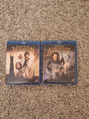 Sagan om Ringen Blu-ray filmer - Två Blu-ray filmer: Sagan om De Två Tornen och Sagan om Konungens Återkomst. Båda har blå plastfodral och färgstarka omslag med motiv från filmerna. Perfekt för dig som gillar fantasy och vill ha klassikerna i samlingen. Skick: 10/10