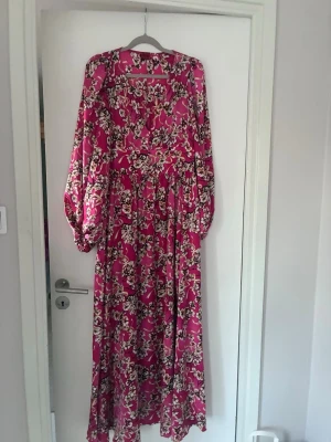 Hugo Boss maxiklänning - Klänning  från Hugo Boss med vackert blommönster i vitt, beige och svart. Klänningen har långa puffärmar och v-ringning med knappar . . Använd en gång för specifikt tillfälle. Som ny! Otroligt fin . Onödigt ha hängande i garderoben ser hellre den används 🩷