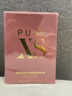 Paco Rabanne Pure XS EdP 50ml - Paco Rabanne Pure XS Eau de Parfum är en lyxig parfym för henne i en snygg rosa kartong med guldiga detaljer. Flaskan rymmer 50 ml och doften är intensiv och sensuell, perfekt för dig som vill sticka ut med en modern och elegant parfym.