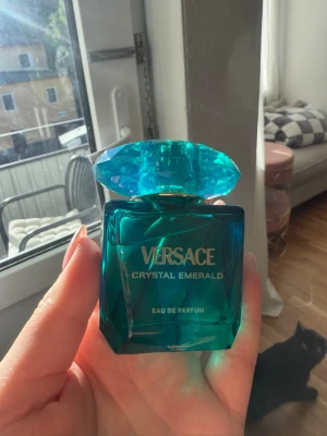 Versace Crystal Emerald parfym 30ml - Versace Crystal Emerald Eau de Parfum i en lyxig smaragdgrön glasflaska med en stor, facettslipad kork. Flaskan har guldtext och en elegant, fyrkantig form som känns exklusiv och modern. Perfekt för dig som vill ha en unik och snygg parfymflaska i samlingen. Endast provad