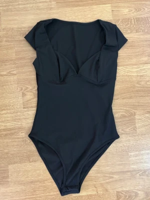 Svart ribbad t-shit body med v-ringning  - Svart v-ringad body, knappt använd. Stretchigt material. Skickas inom 1-2 dagar.