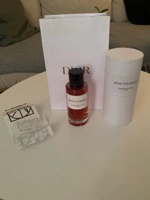 Bois Talisman parfym från Dior, SÖKER BYTE, sker i Uppsala  - Exklusiv parfym från Christian Dior, Bois Talisman. Flaskan är cylindrisk i klart glas med svart kork och har en elegant etikett. Doften har en djup bärnstensfärg och kommer i originalförpackning med tillhörande presentpåse.
