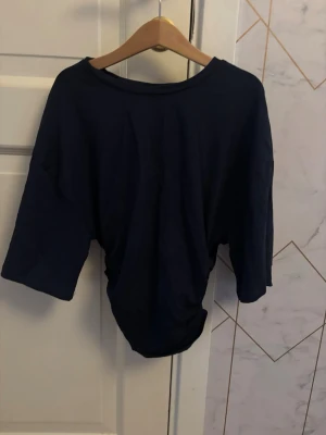 Mörkblå  t-shirt - En enkel och stilren mörkblå t-shirt med tight nertill och lite mer loose upptill. Perfekt för en avslappnad look och lätt att matcha med olika outfits. Tillverkad i mjuk bomull för extra komfort.