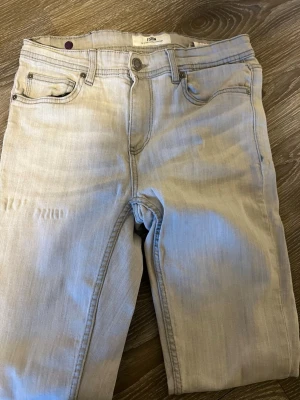 Ljusgrå slim fit jeans från Filippa K - Snygga ljusgrå slim fit jeans från Filippa K med klassisk femficksmodell och diskreta sömmar. Jeansen har en stilren look och är tillverkade i mjukt denimtyg med en lätt stretch för extra komfort. Perfekta för dig som gillar en clean och modern stil.
