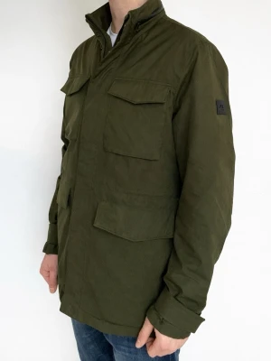 J.Lindberg Bailey Jacka - Jlinberg jacka i den populära modellen bailey, perfekt till våren! Nyskick, inga defekter. Modellen är ca 182 cm. Kontakta mig för fler frågor och funderingar!