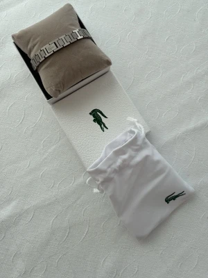 Lacoste armband  - Lacoste armband! Skick är 10/10 använd 1-2 gånger. Det på bilderna är det som medföljer! 20cm men är justerbart till vilken storlek som helst. 