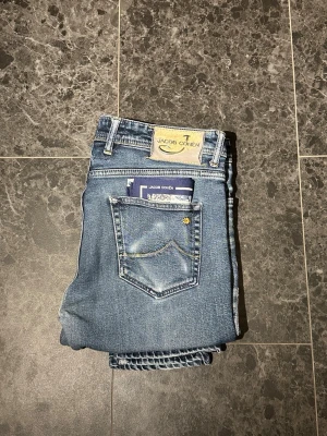 Blåa Jacob Cohen jeans  - Tja! Säljer ett par feta Jacob Cohen med lite slitningar i ett extremt bra skick! jeansen är i storleken 33, bara att höra av sig vid eventuella frågor.