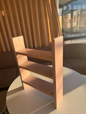  Beige rosa hylla i trä med tre plan - Säljer en stilren hylla i ljusbrunt trä med tre hyllplan. Perfekt för småprylar, böcker eller dekorationer. Hyllan har en enkel och modern design med raka linjer och passar bra på skrivbordet eller i fönstret.