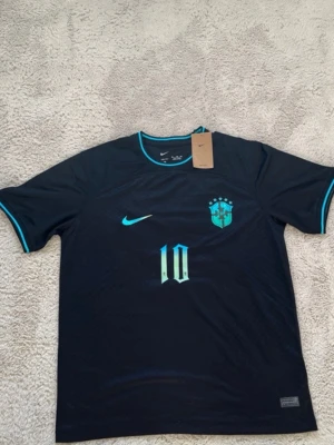 Nike Brasil Neymar Jr matchtröja - Snygg svart Brasilien matchtröja från Nike med Neymar Jr och nummer 10 på ryggen. Tröjan har turkosa detaljer vid krage och ärmslut samt tryck på bröstet och ryggen. Perfekt för dig som älskar fotboll och vill representera Brasilien.