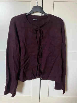 Mörklila stickad kofta från Gina Tricot - Snygg mörklila kofta från Gina Tricot i storlek M. Koftan har långa ärmar och cool snörning framtill istället för knappar. Materialet är mjukt och stickat, perfekt för lager på lager. Rund halsringning och loose passform ger en chill vibe.