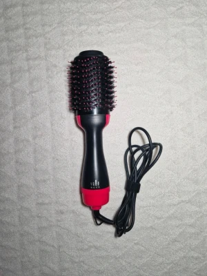Svart och rosa varmluftsborste - Elektrisk varmluftsborste i svart och rosa med rund borste. Handtaget är ergonomiskt format och perfekt för att styla och torka håret samtidigt. Materialet är plast och metall.