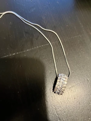 Silverhalsband med glittrande hänge - Snyggt silverfärgat halsband med ett rektangulärt hänge täckt av små gnistrande stenar. Kedjan är tunn och elegant, vilket gör att hänget verkligen står ut. Perfekt accessoar för att lyfta vilken outfit som helst. Lådan medföljer inte.