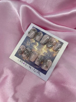 SteelKiss (S);Short Ballerina - Snygga handgjorda press-on naglar i nude med unika handmålade silverdetaljer och 3D-metallmotiv som stjärnor och kedjor. Naglarna har en ballerina, kort form och är handgjorda för en trendig look. Perfekta för dig som vill sticka ut med coola accessoarer på naglarna.S: 15 mm, 11,5 mm, 12 mm, 11 mm, 9 mm 