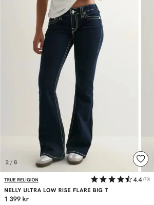 True Religion mörkblå flare jeans - Snygga mörkblå jeans från True Religion med låg midja och utsvängda ben. Tydliga vita kontrastsömmar och klassiska fickor med broderad logga bak. Storlek W25 vilket ungefär motsvarar S. Aldrig använda, bara testade.