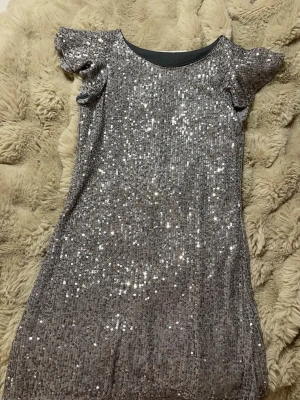 Glittrig silverklänning från KappAhl - KappAhl paljettklänning, stl 140 Festlig barnklänning i mörkgrå med paljetter. Bra skick, använd få gånger. 💎 Perfekt till nyår, kalas eller fest!