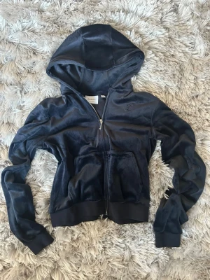 Juicy Couture blå velour hoodie  - Snygg mörkblå velour hoodie från Juicy Couture. Klassisk zip-up modell med huva och fickor framtill. Mjuk och glansig velour. Broderad Juicy-logga på bröstet. Perfekt till både vardag och mys, eller för en trendig throwback-look. I fint begagnat skick 🌸 Storlek: XS / S (se bild på tag)