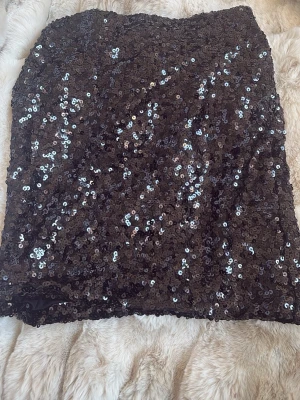 Svart paljettkjol - Säljer en svart kortkjol täckt med glittriga paljetter. Köpte i spanien men passade inte mig så därav aldrig använt och prislappen är kvar. Storleken är xs/s