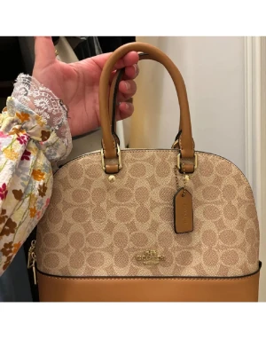 Coach handväska i beige och brunt - Stilren handväska från Coach i beige canvas med klassiskt. Ej äkta. 