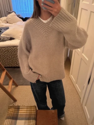 Grå/grön stickad mohair tröja - Mysig grå/grön stickad tröja med oversized passform och breda ribbade muddar. Tröjan har V-formad struktur vid halsen och är tillverkad i ett mjukt, tjockt material. Perfekt för lager på lager och en avslappnad look.