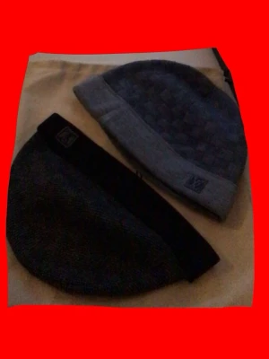 Två Louis Vuitton mössor 600KR STYCK - Säljer två stilrena mössor från Louis Vuitton. Ena är grå med vävt rutmönster och vikt kant med LV-logga, den andra är svart med diskret LV-märke. Båda är stickade och perfekta för kalla dagar.