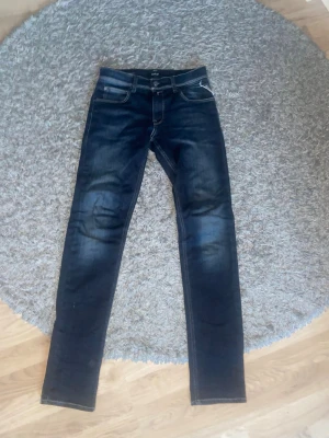 Replay jeans slim fit - Snygga mörkblå slim fit jeans med lätt slitning och klassiska fem fickor. Jeansen har kontrastsömmar och en modern passform som sitter tajt längs benen. Perfekta för en trendig och avslappnad stil.