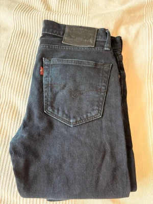 Svarta Levi's 511 jeans - Snygga svarta Levi's 511 jeans i klassisk rak modell. Jeansen har fem fickor, Levi's ikoniska röda etikett på bakfickan och patch med logga i midjan. Tillverkade i mjukt denimtyg som sitter skönt och passar till många olika stilar. W 29 L 32 en liten skada på höger knät (se bild 4) 