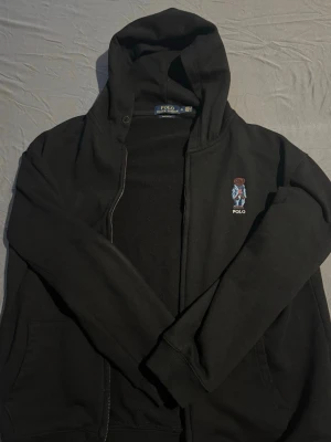 Svart hoodie från Polo Ralph Lauren - Svart hoodie från raulph lauren. Köpt i USA i butik. Det står att tröjan är XL men den är custom fit och passar M/S. Perfekt för nån mellan 175-185. Den har inga slitage eller något.  