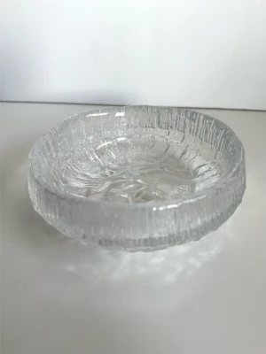 Iittala - ”Lunaria” skål i klar glas - Designklassiker från Iittala, ”Lunaria” glasskål i klart konstglas med texturernas yta. Designad av Tapio Wirkkala för Iittala och kännetecknas av sin isliknande strukturerade yta. Lunaria-serien är starkt representativa för Wirkkalas formspråk inom glaskonst, som passar både som bruksföremål och samlarobjekt. 16 cm i diameter och 5 cm hög. Mycket gott skick, som ny!
