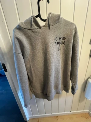 Grå hoodie från gina - Säljer en grå hoodie. Hoodien har huva och ribbade muddar vid ärmslut och nederkant. Perfekt för en chill och avslappnad stil. Materialet känns mjukt och bekvämt. Lite sliten vid luvan men annars ganska bra skick