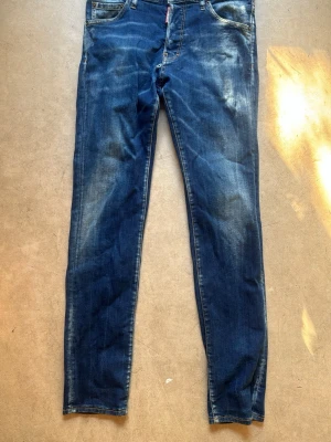 DSQ jeans  - Snygga blå slim fit jeans från Dominar med slitningar och ljusa tvättade partier. Klassisk femficksmodell med kontrastsömmar och bälteshällor. Jeansen har en modern passform och är tillverkade i denim med en skön känsla.