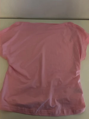 Rosa topp från SHEIN i polyester - En enkel och stilren rosa topp från SHEIN i mjuk polyester. Toppen har korta ärmar och en klassisk rund halsringning. Perfekt att matcha med jeans eller kjol för en avslappnad look.