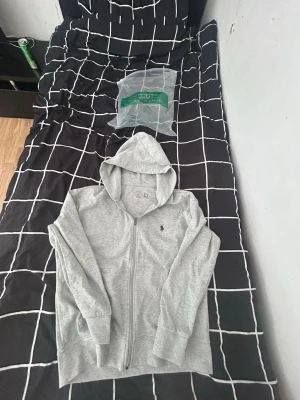 Polo Ralph Lauren Zip Hoodie Grå – Strl S – Helt Ny med Påse - Säljer en helt ny Polo Ralph Lauren zip hoodie i storlek S. Hoodien är oanvänd och kommer fortfarande med originalpåse. Stilren grå färg med klassisk Polo Ralph Lauren-logga på bröstet. Perfekt för både vardag och casual outfits.  ✔️ Storlek: S ✔️ Skick: Helt ny ✔️ Färg: Grå ✔️ Med dragkedja och huva ✔️ Originalpåse ingår ✔️ Mjuk och bekväm passform ✔️ Äkta Polo Ralph Lauren-design 📦Fraktar under 24 timmar garanterat  💰 Pris: Kan diskuteras vid snabb affär.