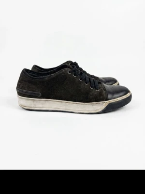 Lanvin cap toe brunröda - Snygga svarta lanvinss i mocka och tåparti i slätt läder. Skorna har svarta skosnören och en vit sula med svarta detaljer. Perfekta för en avslappnad streetstil och passar till det mesta i garderoben. Lite slitna på sulan men fortfarande väldigt mycket att ge och de perfekta skorna till sommaren
